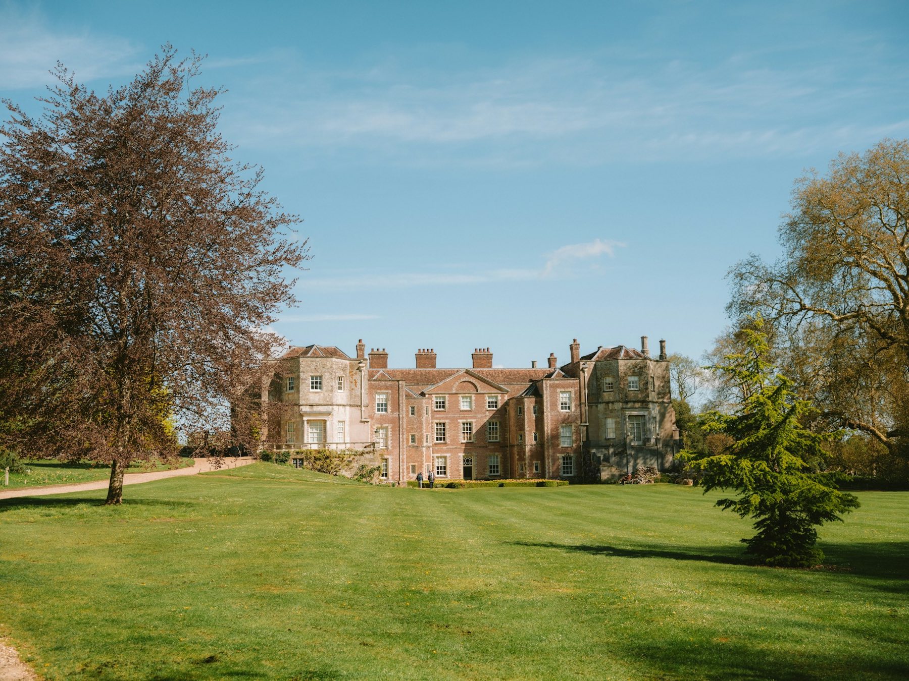Historic manor house with mature trees across a large lawn